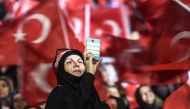 Women wave Turkish national flags as a woman takes pictures on March 5, 2017 in Istanbul during a pro-government women meeting. Some 12,000 women filled on March 5 an Istanbul arena in support of a 