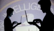 People are silhouetted as they pose with laptops in front of a screen projected with binary code and a Central Inteligence Agency (CIA) emblem, in this picture illustration taken in Zenica, Bosnia and Herzegovina October 29, 2014. REUTERS/Dado Ruvic/File 