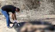 A rescue worker removes dead bodies of migrants, that were buried by people on the beach, after they were recovered by the Libyan Red Cross to be re-buried in a cemetery designated for migrants, in the western coastal city of Sabratha, Libya, March 7, 201