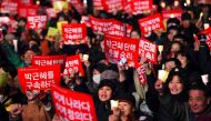 South Korean demonstrators hold up red banners reading 