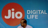 This photo taken on March 7, 2017 shows an Indian man sitting in front of a sign for Indian mobile service provider Jio at a bus stop in Mumbai. AFP / Indranil Mukherjee