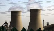 A man looks over a fence towards chimneys of a coal-burning power station located on the outskirts of Beijing, REUTERS/David Gray
