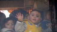 A child waves from the window of a bus as Syrians who were evacuated from Waer, the last opposition-held district of Homs, arrive in the northern Syrian town of al-Bab on March 19, 2017, under a controversial Russian-supervised deal to bring Syria's third