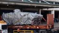 This file photo taken on January 26, 2017 shows a worker walking past an impounded tarpaulin-covered armoured troop carrier Terrex vehicle belonging to the Singapore military, after it was placed by crane onto a truck, at a customs and excise facility in 