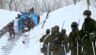 Firefighters carry a survivor they rescued from the site of an avalanche. JIJI PRESS / AFP.