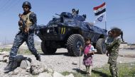 Displaced Iraqi children, who fled their homes in the Old City in western Mosul due to the ongoing fighting between government forces and Islamic State (IS) group fighters, are seen looking towards a security forces member ahead of being taken to the Hamm