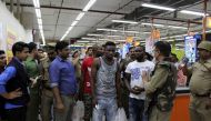This photo taken on March 27, 2017 shows Indian police and onlookers surrounding African nationals at a shopping mall in Greater Noida. Hundreds of residents of an Indian city where a teenage boy died of a suspected drug overdose went on a violent rampage