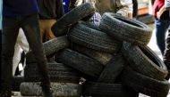 A Palestinian protestor takes cover behind a pile of tires during clashes with Israeli security forces following a weekly demonstration against the expropriation of Palestinian land by Israel in the village of Kfar Qaddum, near Nablus, in the occupied Wes