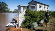 Residents look at a cow, which drowned in floodwaters caused by Cyclone Debbie, that they recovered on their property in North MacLean, Brisbane on April 1, 2017. AFP /  Patrick HAMILTON
