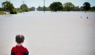 Seth Skirving, 5, watches floodwaters of the Logan River, caused by Cyclone Debbie, flow over the Mt Lindesay Highway in Waterford West near Brisbane on April 1, 2017. AFP / Patrick HAMILTON