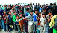 Displaced Iraqis, who fled Mosul due to the ongoing fighting between government forces and Islamic State (IS) militants, receive food at the Hammam Al Alil camp, south of Mosul, yesterday.