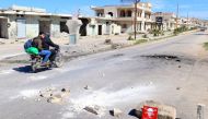 Men ride a motorbike past a hazard sign at a site hit by an airstrike on Tuesday in the town of Khan Sheikhoun in rebel-held Idlib, Syria April 5, 2017. The hazard sign reads, 
