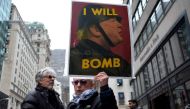 An anti-war protester displays a placard against US President Donald Trump during a demonstration in front of the Trump Tower in New York on April 7, 2017, to protest the US air strike in Syria.  AFP / Jewel SAMAD