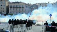 Policemen stand in front of smoke during a clash with protesters after a meeting of the French far-right Front National (FN) party candidate for the presidential election in Ajaccio, on the French Mediterranean island of Corsica, yesterday.