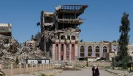 A woman walks in front of the remains of the University of Mosul, which was burned and destroyed during a battle with Islamic State militants, in Mosul, Iraq, April 10, 2017. REUTERS/Marko Djurica
