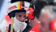 Ferrari's German driver Sebastian Vettel talks to one of his engineers in the garage during a practice session ahead of the Formula One Bahrain Grand Prix at the Sakhir circuit in the desert south of the Bahraini capital, Manama on April 14, 2017. / AFP /