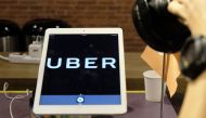 A photographer (R) takes pictures of the logo for ride-hailing service Uber during a press conference in Taipei on April 13, 2017.   AFP / SAM YEH
