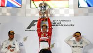 First place Ferrari Formula One driver Sebastian Vettel of Germany (C) holds the trophy on the podium with second place Mercedes Formula One driver Lewis Hamilton of Britain (L) and third place Mercedes Formula One driver Valtteri Bottas of Finland. REUTE