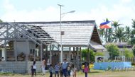 Students with their teacher walk past a flag near the airport, during the visit of Defence Secretary Delfin Lorenzana to the Philippine-claimed island Thitu in The Spratlys on April 21, 2017. AFP / Ted Aljibe