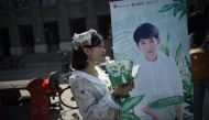 This picture taken on April 14, 2017 shows a woman handing out leaflets during an event for fans of China's boy band sensation TFBoys 