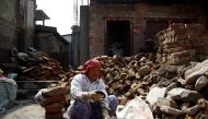 A woman cleans bricks collected from her house that collapsed during the 2015 earthquake, to rebuild her house in Bhaktapur, Nepal, on April 21, 2017. Photo: Reuters