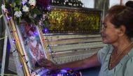 Jiranuch Trirat's mother touches a photo of her slain 11-month old granddaughter Natalie at a temple in Phuket on April 27, 2017.   AFP / LILLIAN SUWANRUMPHA
