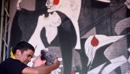 Refugee resident in Spain, Hassanna Aailia, from Western Sahara embraces Pilar Ostolaza, refugee in France during the Spanish Civil War, in front of a reproduction of Picasso's Guernica during the Ongi Etorri Errefuxiatuak (Welcome Refugees) rally in the 