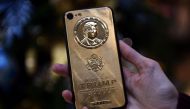 FILE PHOTO: An employee of Caviar Phones, a Russian-Italian company specializing in smartphone customization, displays a special gold-plated iPhone 7 smartphone bearing the likeness of  Trump (AFP) 