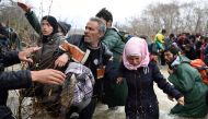 FILE PHOTO: Refugees trying to cross a river on their way to Macedonia from a makeshift camp near the Greek village of Idomeni on March 14, 2016. AFP / Daniel Mihailescu