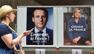 A woman walks past portraits of French presidential candidates, former economy minister Emmanuel Macron (L) and far-right National Front leader Marine Le Pen (R), after her voting at a polling station at the French embassy in Tokyo on May 7, 2017. / AFP.