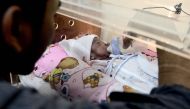 This photo taken on March 17, 2017 shows Prayogi feeding his daughter Maryamah Sudigyo, who was born prematurely, as she rests in an incubator in their home in Bogor. AFP / GOH Chai Hin 