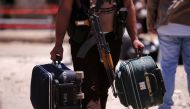 A rebel fighter carries suitcases and his weapon prior to boarding a bus as rebel fighters and their families evacuate the besieged Waer district in the central Syrian city of Homs, after an agreement reached between rebels and Syria's army, Syria May 21,
