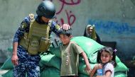 A member of the Iraqi forces plays with children on the outskirts of the old city of Mosul, yesterday, after the area was retaken by Iraqi forces during the ongoing offensive to clear it from Islamic State group fighters.