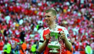 Arsenal's German defender Per Mertesacker holds the trophy as he celebrates on the pitch after their win over Chelsea in the English FA Cup final against Chelsea at Wembley Stadium in London on Saturday. 