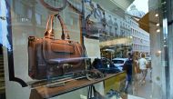 Pedestrians are reflected in the window of a luxury goods store in Paris, France
