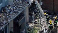 Firefighteres work amongst debris at the base of the charred remnains of the Grenfell Tower block in Kensington, west London, on June 17, following the June 14 fire at the residential building. / AFP.