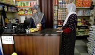 A Syrian refugee purchases goods at a shop, which accepts the United Nations' World Food Programme cards, in Beirut on June 14, 2017. Displaced Syrian families in Lebanon are using electronic cards, topped up each month by the United Nations' World Food P