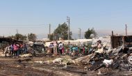 Syrian refugees look at the damage after a fire engulfed part of the Tel al-Sarhoun refugee camp near the village of Bar Elias in Lebanon's eastern Bekaa valley on July 4, 2017. (AFP / HASSAN JARRAH)