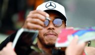 Mercedes' British driver Lewis Hamilton signs autographs for fans.