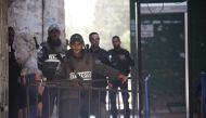 Israeli security forces wait as Palestinians perform prayer near new security metal detectors, outside one of the main entrances to the Al-Aqsa mosque, refusing to enter because of the detectors installed by Israel as the holy site re-opened for the first