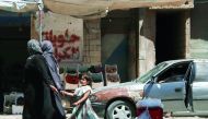 A Syrian girl holds a woman’s hand as she walks down a street in the central Syrian rebel-held town of Talbiseh, north of Homs, yesterday.