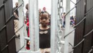 A girl who crossed the Canada-US border with her family, claiming refugee status in Canada,as she looks through a fence at a temporary detention centre in Blackpool, Quebec on August 5, 2017. AFP / Geoff Robins