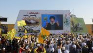 Supporters of Lebanon's Hezbollah leader Sayyed Hassan Nasrallah display Hezbollah and Lebanese flags as they listen to him via a screen during a rally marking the 11th anniversary of the end of Hezbollah's 2006 war with Israel, in the southern village of