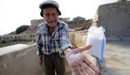 Elias al-Najar, 93, displays salt flakes in the coastal Lebanese town of Anfeh north of the capital Beirut on July 21, 2017.  AFP / Ibrahim Chalhoub