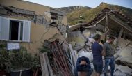 A man sits on a bucket as others look on near a wracked building after 4.0-magnitude richter scale earthquake hit Ischia Island's Casamicciola Terme of Naples, Italy on August 22, 2017. ( Alessio Paduano - Anadolu Agency ).
