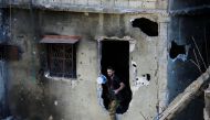 A Palestinian Fatah fighter walks through a hole in a wall inside the Ain el-Hilweh refugee camp near Sidon, southern Lebanon, August 23, 2017. REUTERS/Ali Hashisho
