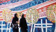 Two Iranian women walk along a street past a mosaic mural on Jaunary 14, 2017. (AFP / Atta Kenare) 
