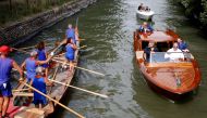 Actor George Clooney (L) is greeted by a boat crew as he arrives for the movie 