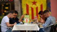 A group of tourists sit in a terrace in front of a graffitti depicting a Catalan pro-independece flag 'Estelada' on September 13, 2017, in Barcelona. AFP / Lluis Gene