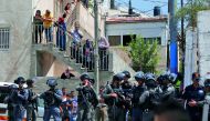 Israeli security forces and Palestinian residents watch as the home of the Abu Farah family is demolished by municipality workers at Al Tur, yesterday.